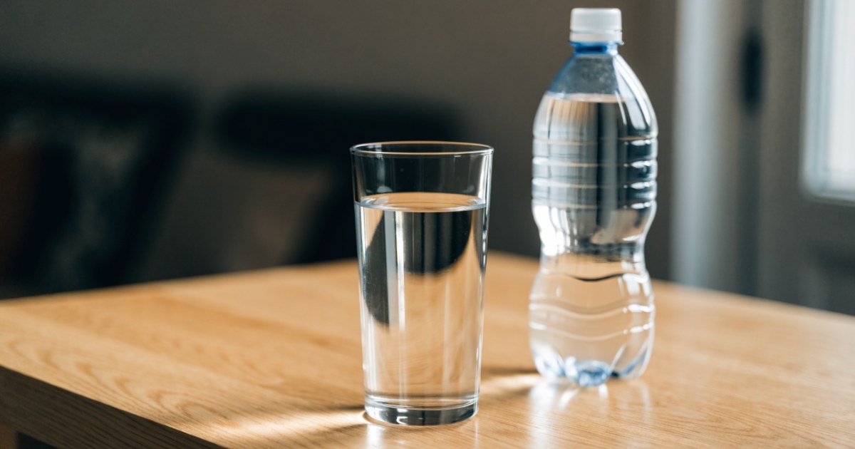 Mikroplastik im Gehirn: Glas Wasser und Plastikflasche auf einem Holztisch