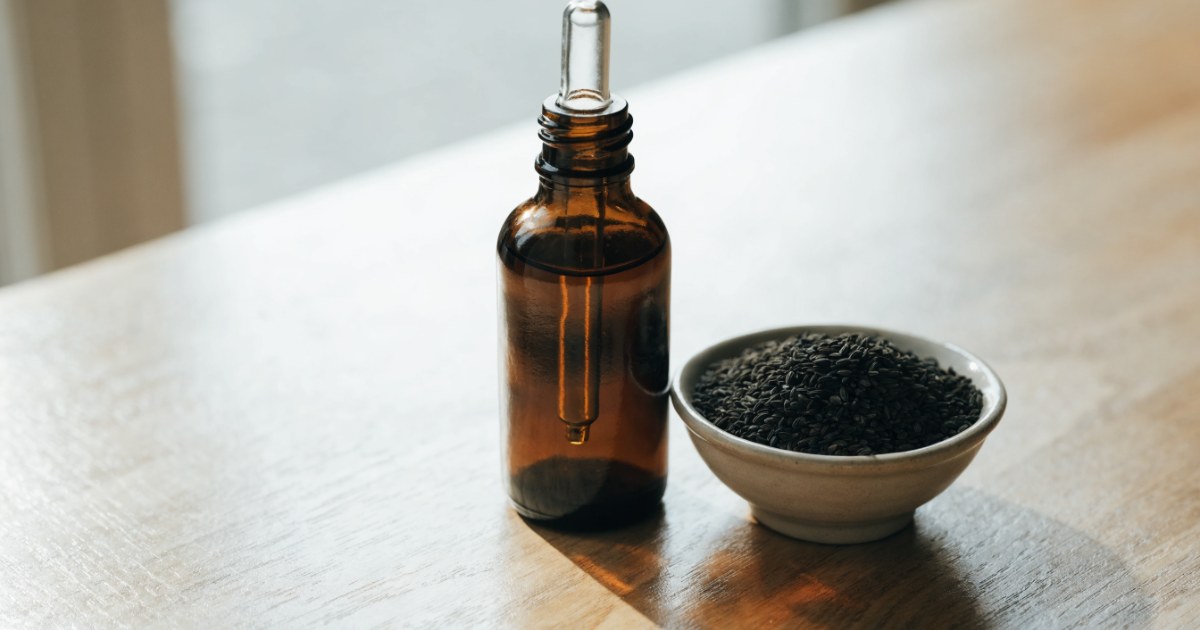 Schwarzkümmelöl bei Histaminintoleranz: dunkle Flasche mit Pipette und Schale mit Schwarzkümmelsamen